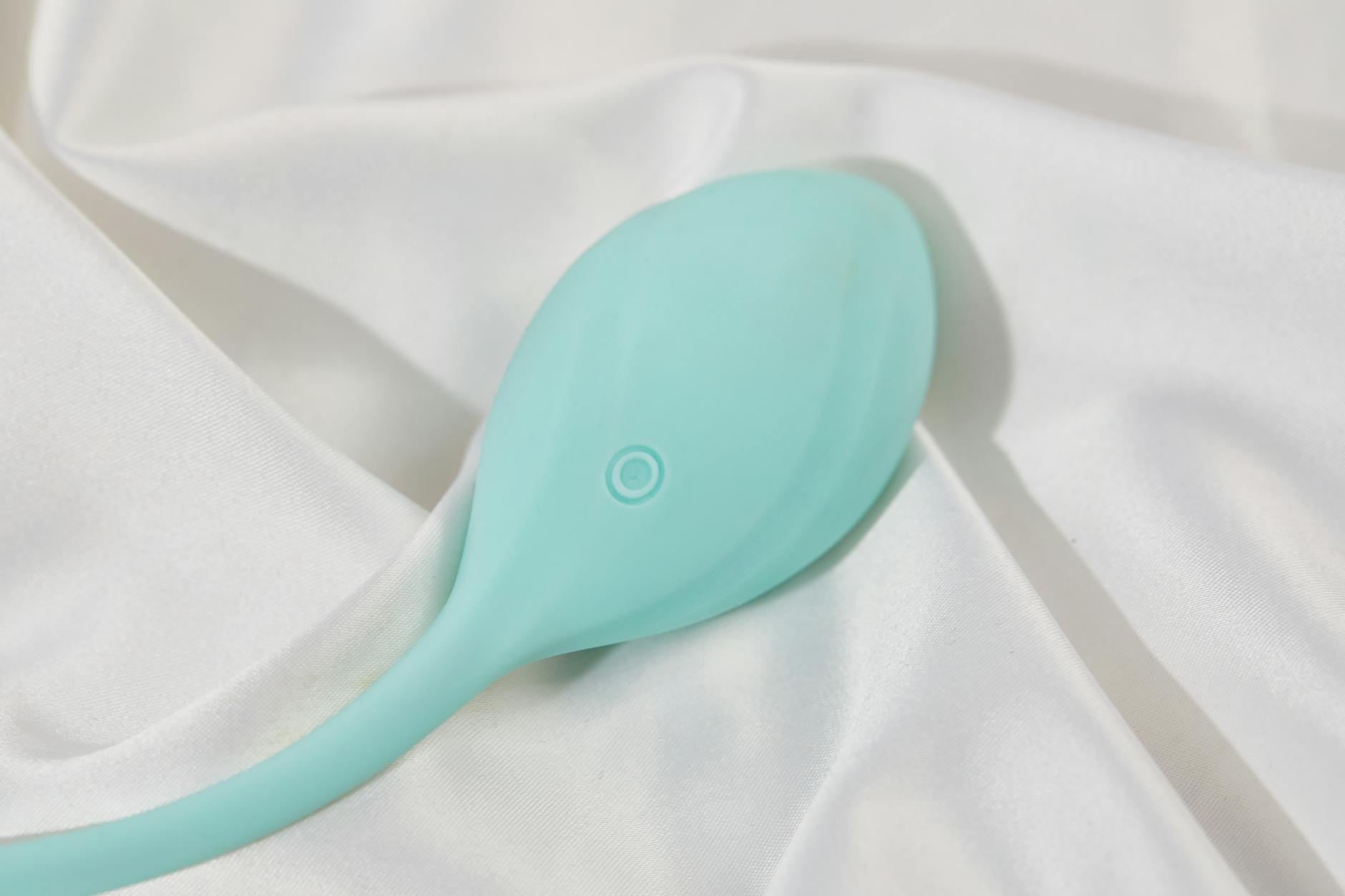 Vibrateur élégant sur tissu blanc lisse, représentant un plaisir sensuel et raffiné