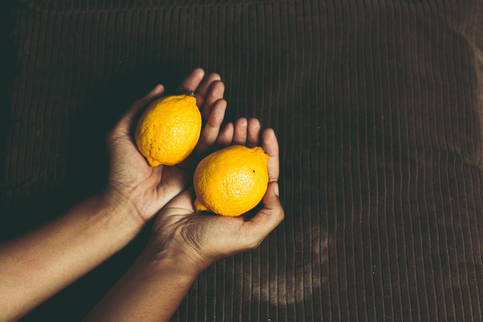 Hands holding fresh lemons, symbolizing natural pleasure and vitality