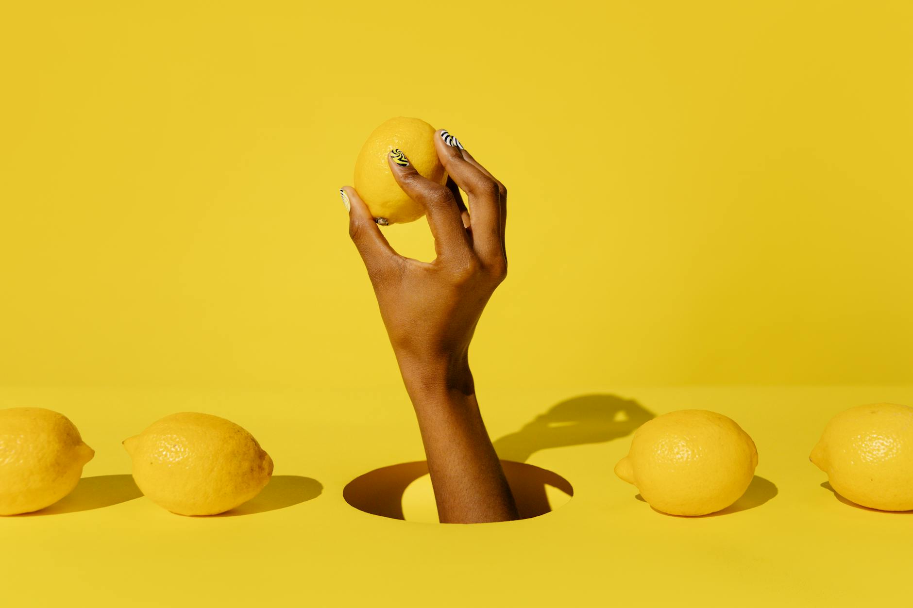 Main tenant un citron frais sur fond jaune vibrant, symbolisant la fraîcheur et le renouveau du plaisir