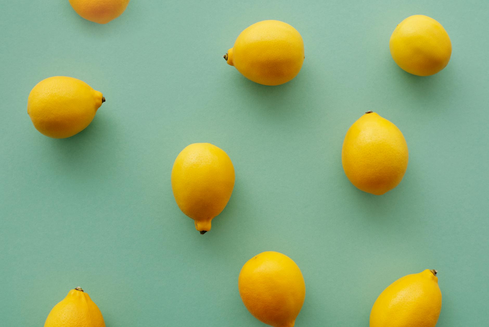 Bright yellow lemons arranged on a pastel green background, representing the fresh, clean design of Lemon Clit Store vibrators