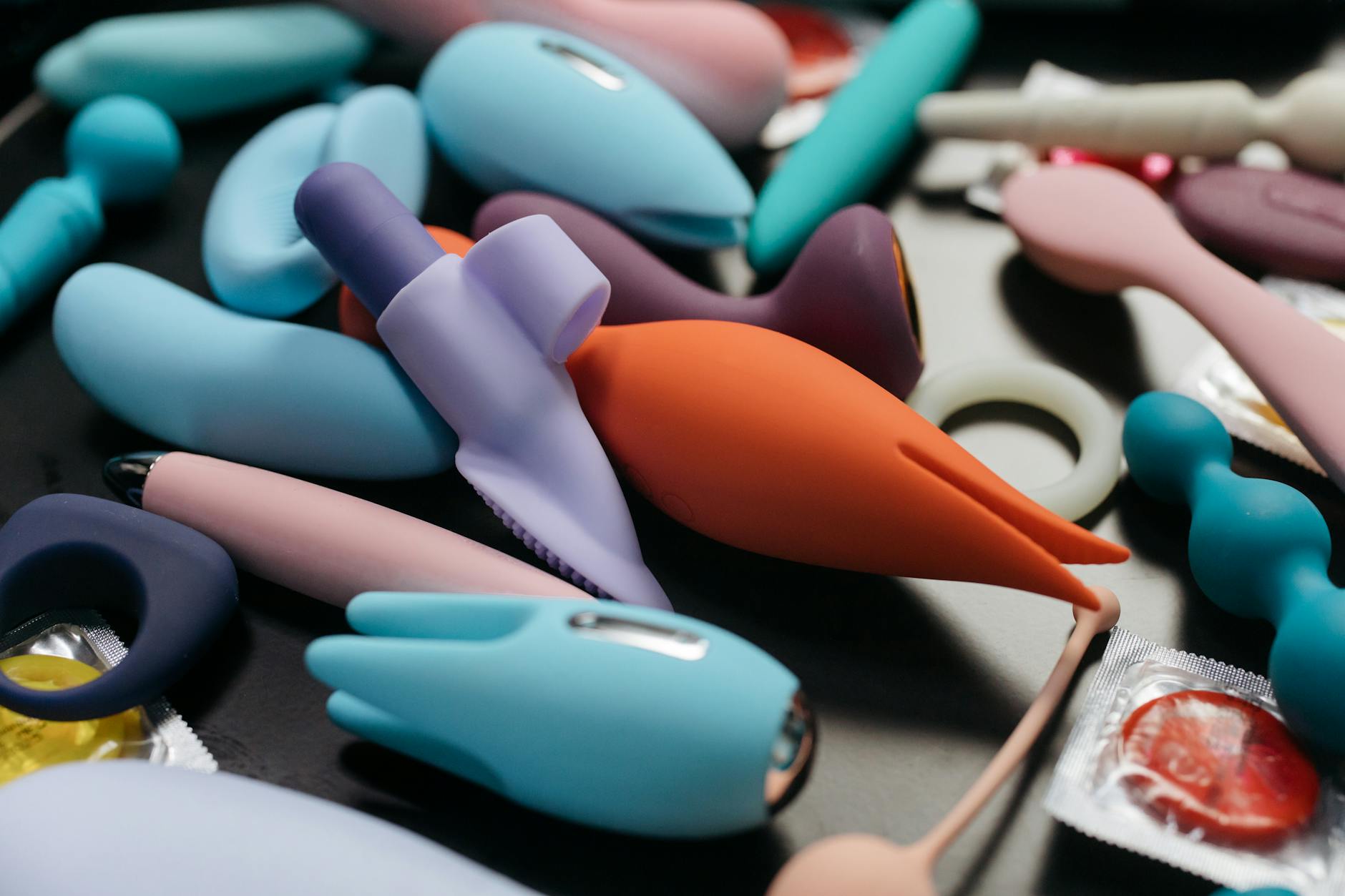Close-up of a woman holding a pink vibrator, with art books in the background, emphasizing intimate personal exploration