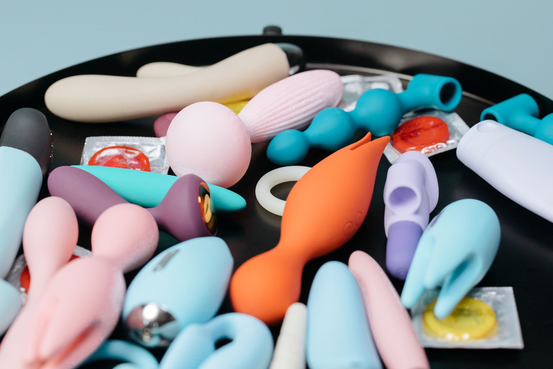 A collection of lemon and colorful clitoral vibrators arranged on a black surface