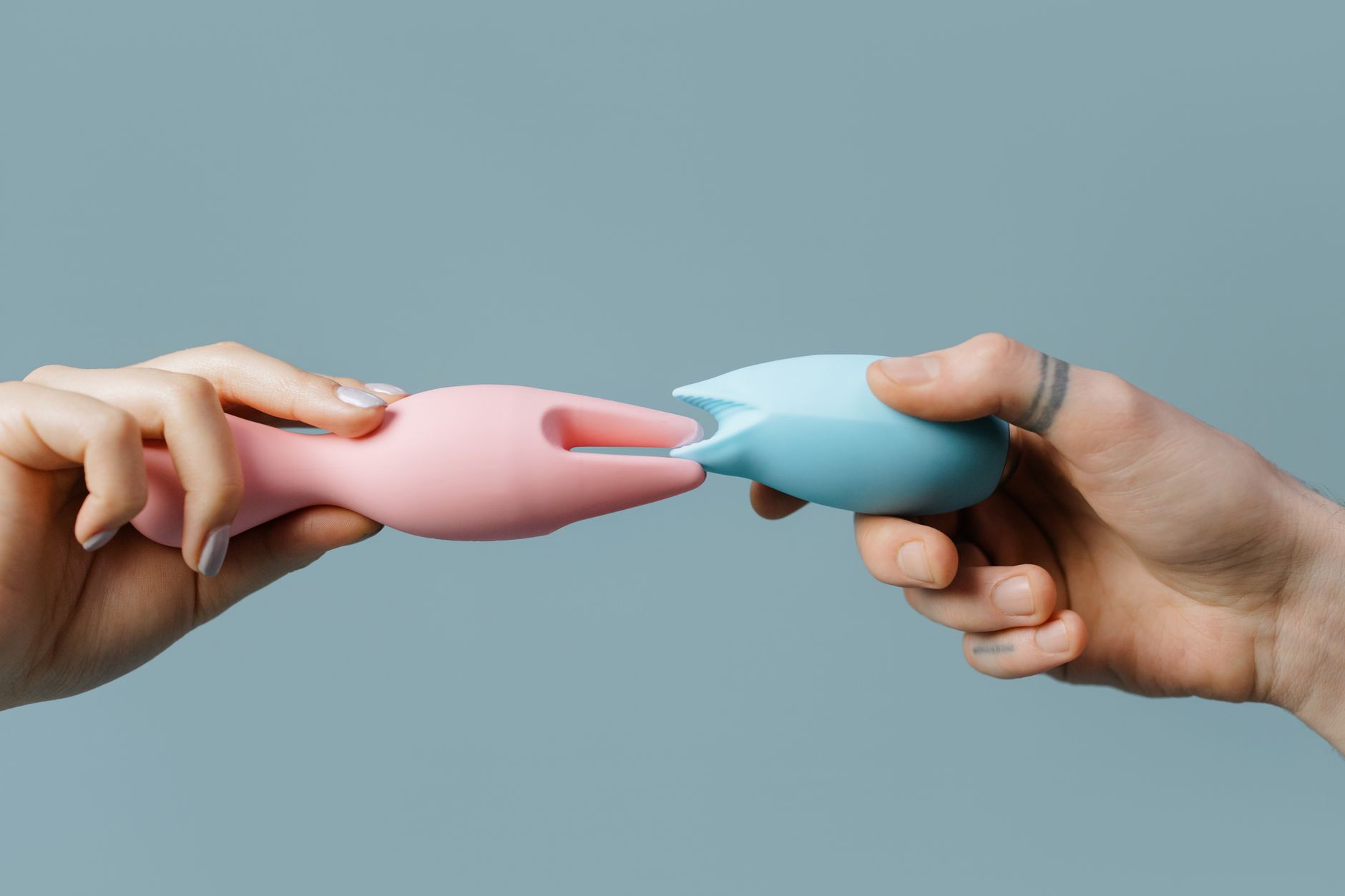 Femme tenant deux vibrateurs colorés contre un fond violet