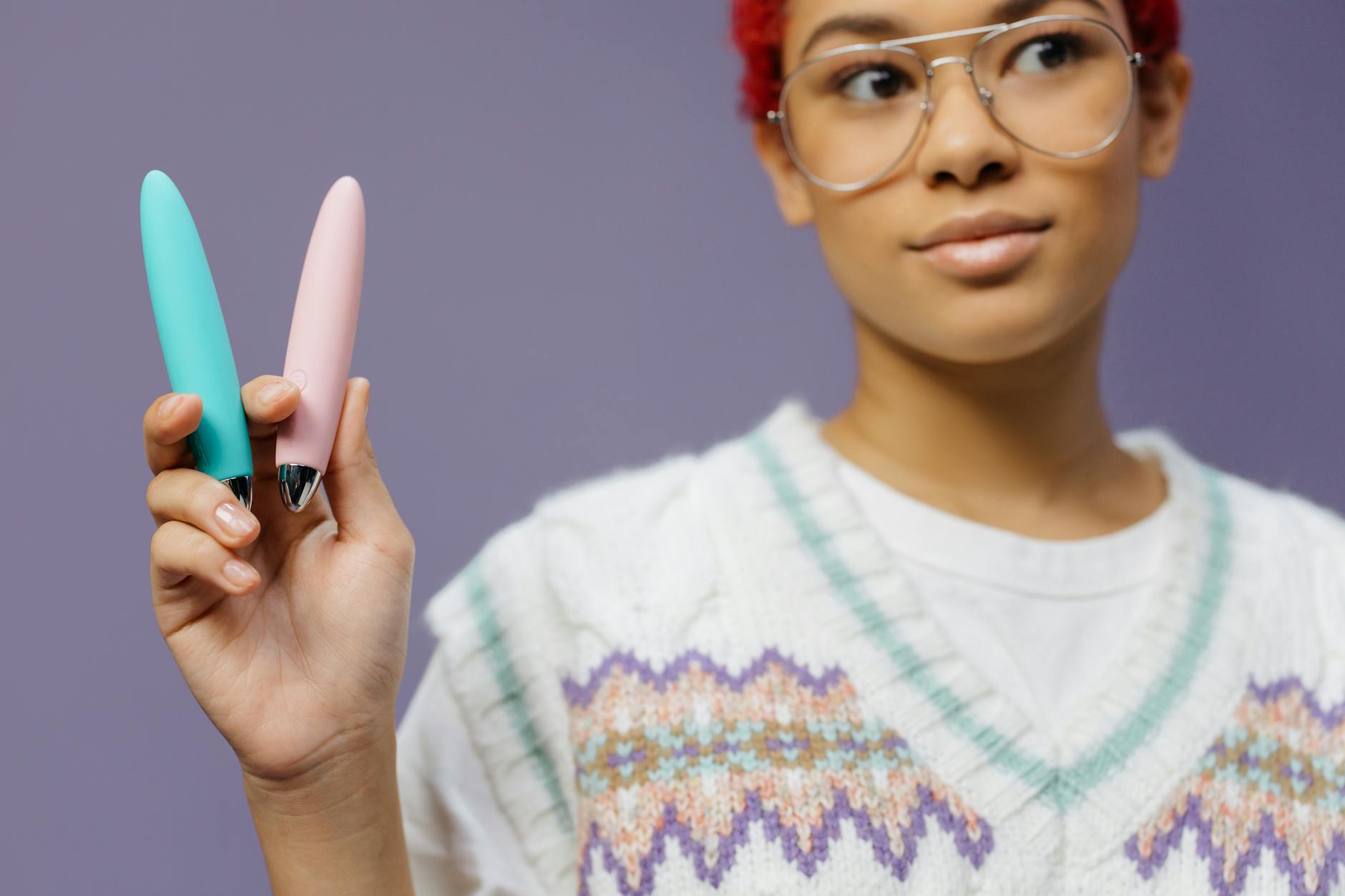 Woman holding colorful vibrators against a purple background