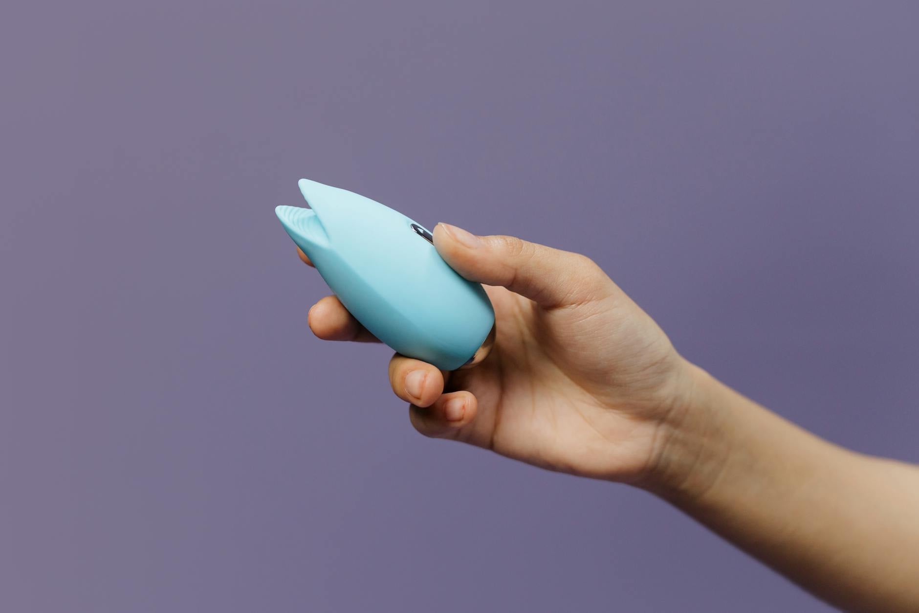 Un vibrateur citron bleu tenu en main sur un fond violet, promouvant l'estime de soi et la sexualité