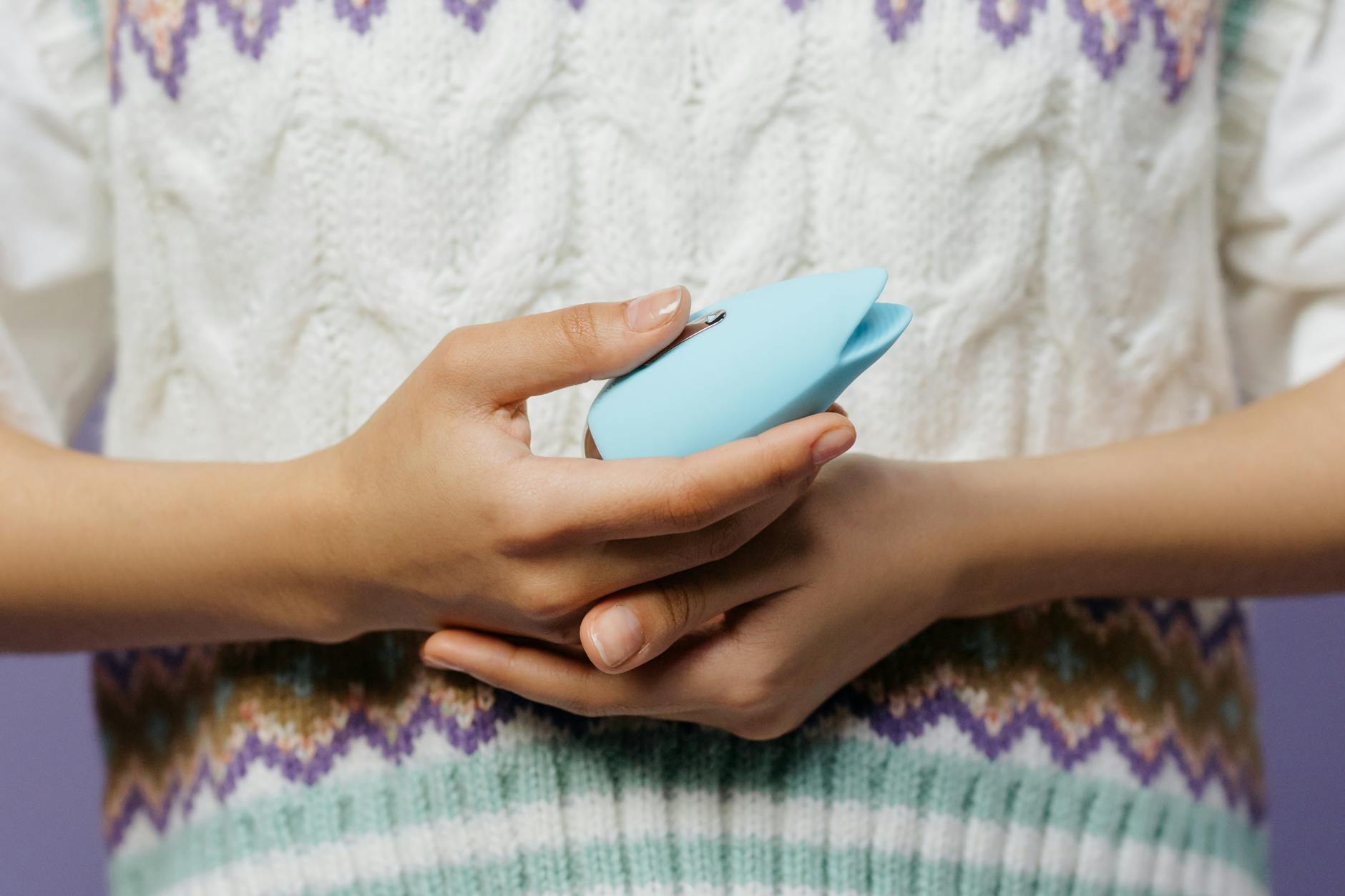 Gros plan des mains tenant un vibrateur contre un pull tricoté bleu
