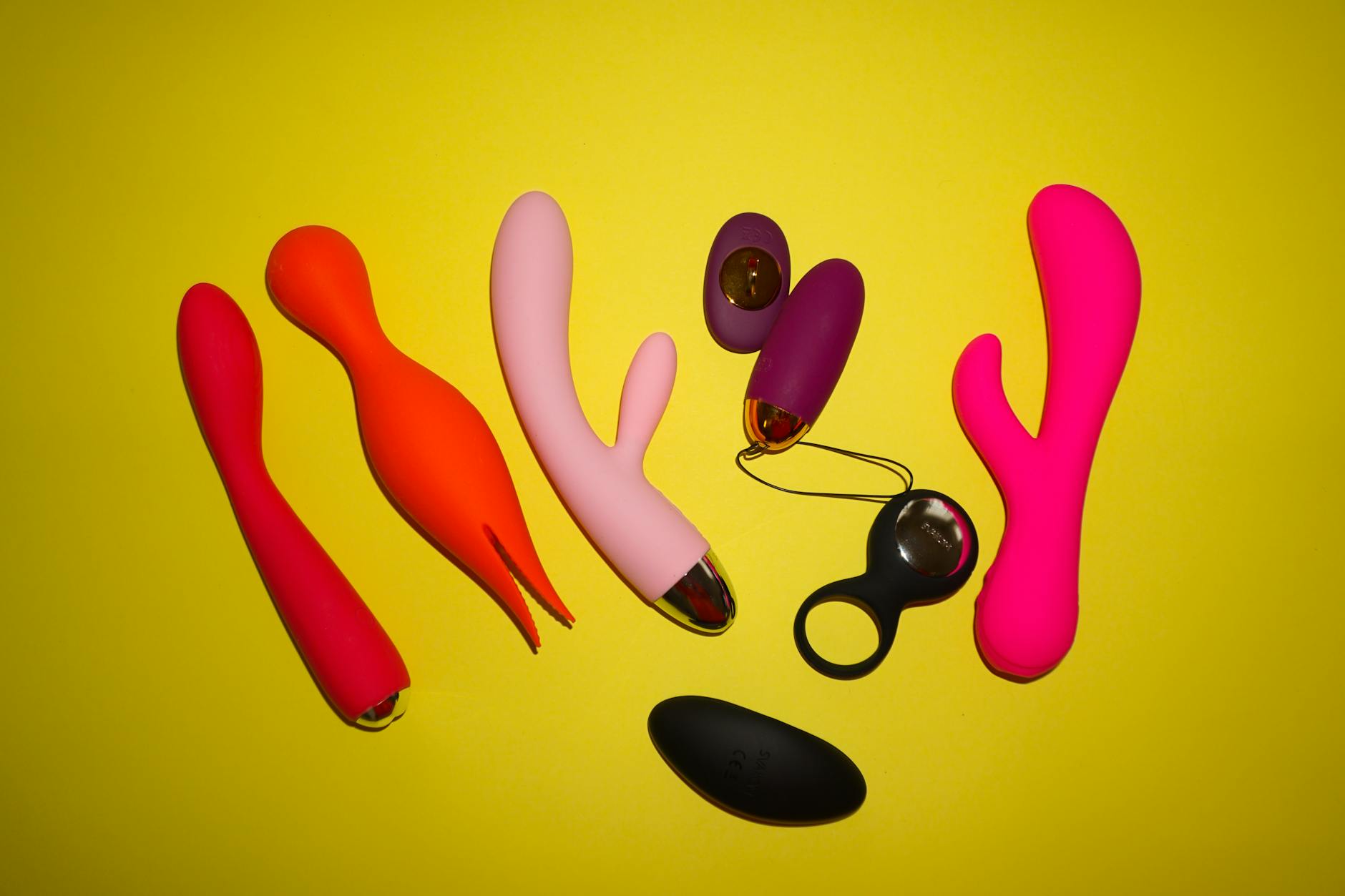 A hand holding a bright vibrator against a minimalist background, symbolizing comfort with pleasure